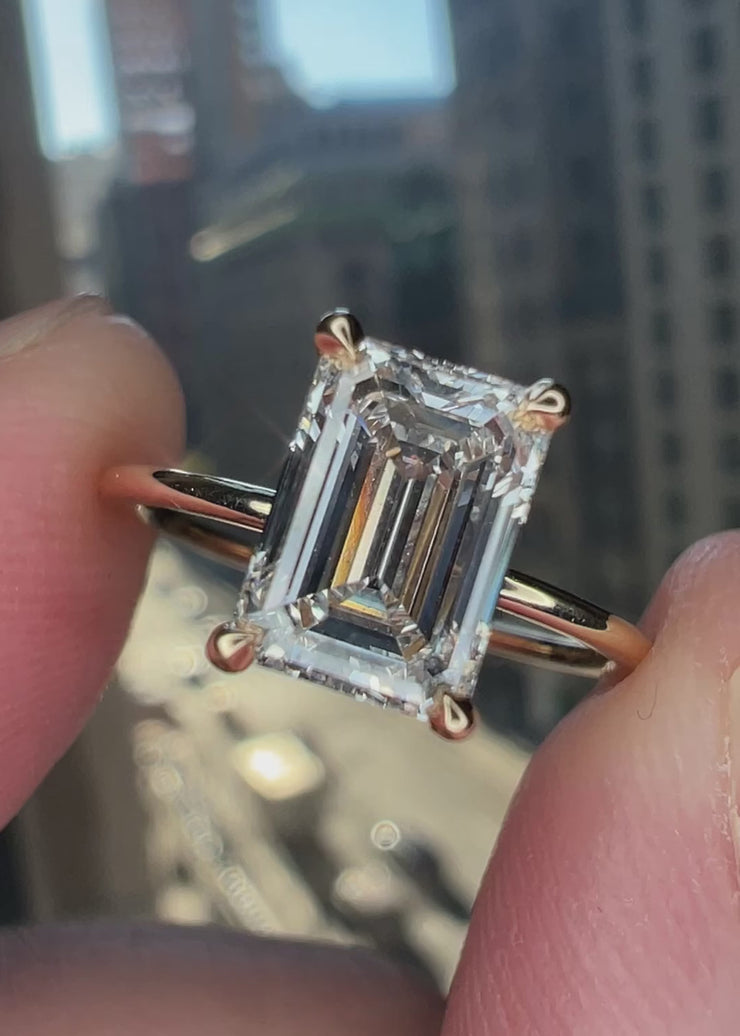 super delicate emerald cut lab grown diamond yellow gold engagment ring with clawed prongs and a wedding band can sit flush