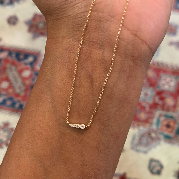 Rise 4 diamond gradating necklace with petite stones and delicate adjustable chain in 14k yellow gold by Dana Walden Bridal on hand 