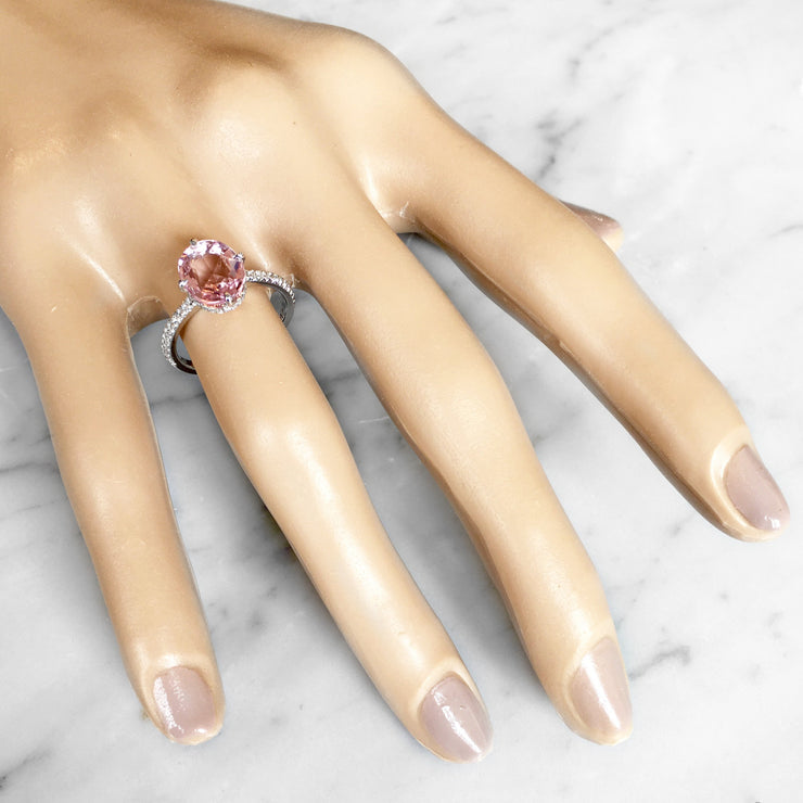 Unique 2.25 carat peach pink sapphire engagement ring with delicate band and diamond accents on hand