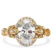 An oval diamond solitaire with leafy nature inspired details and conflict-free diamond accents. Yellow Gold engagement ring made in New York City by Dana Walden Bridal.