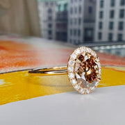 Natural Champagne Diamond Engagement Ring in Yellow Gold with a delicate diamond halo side view on a yellow book with NYC in the background