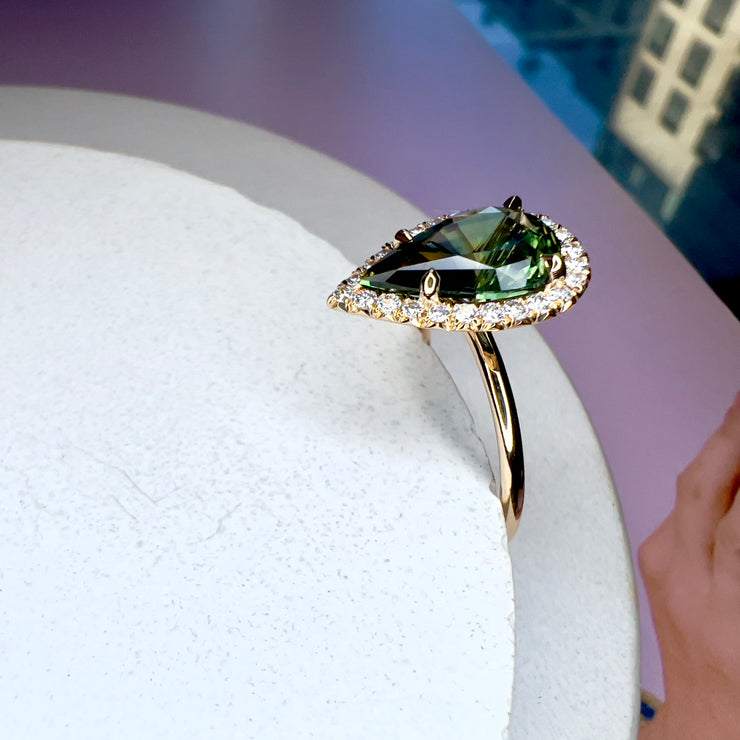 Lennox 3.04 carat green sapphire in pear shape with conflict free white diamond halo in 14k yellow gold setting with thin dainty band from side profile 