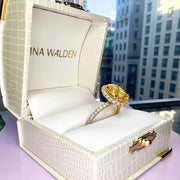 shown from the side in a Dana Walden Ring box with thr NYC skyline in the background - Andaz 4.61 Carat Natural Oval-Cut Yellow Sapphire Halo Engagement Ring Eco-Friendly 18k Yellow Gold