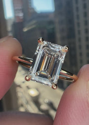 super delicate emerald cut lab grown diamond yellow gold engagment ring with clawed prongs and a wedding band can sit flush