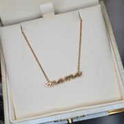 A 14k gold necklace that says MAMA in script. Handmade by DANA WALDEN JEWELRY NYC.