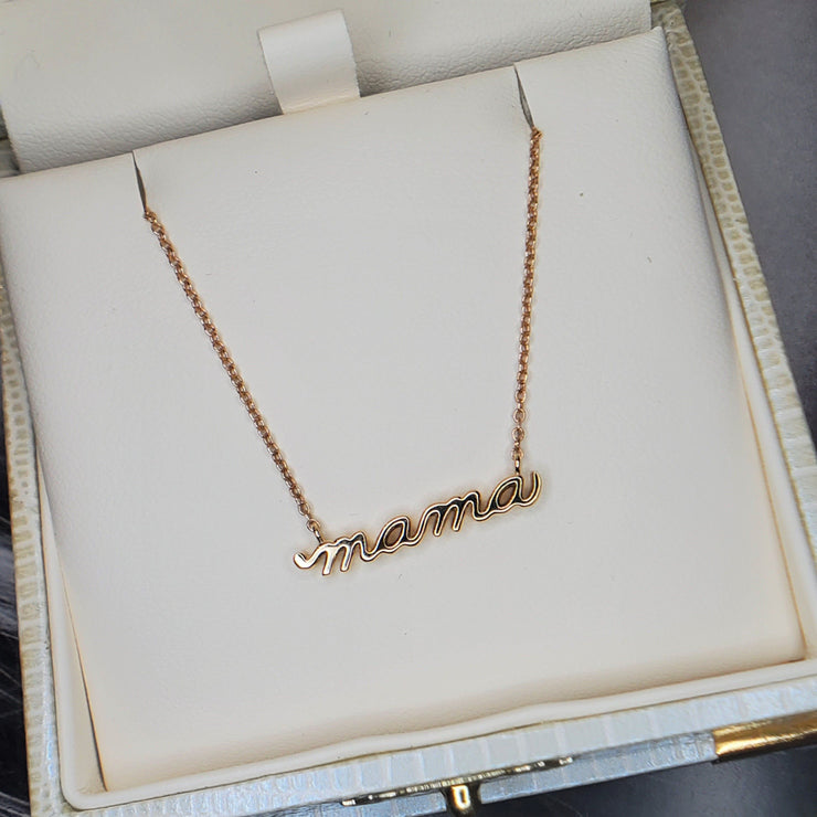 A 14k gold necklace that says MAMA in script. Handmade by DANA WALDEN JEWELRY NYC.