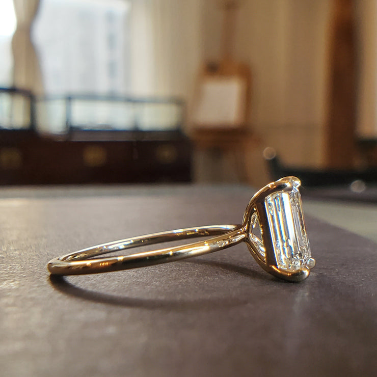 Side profile of Silas emerald cut lab grown engagement ring in 14k yellow gold setting with thin dainty band and hidden halo