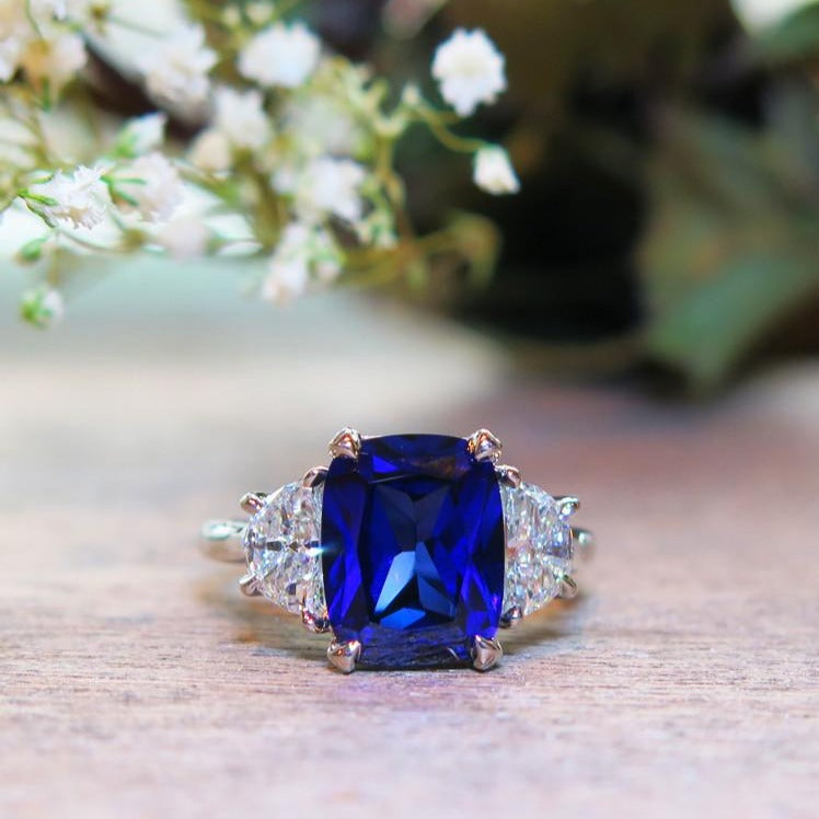https://www.danawaldenbridal.com/cdn/shop/products/Alexandra-3-Stone-Cushion-Cut-Engagement-Ring-Lab-Created-Blue-Sapphire-Conflict-Free-Diamonds-Eco-Friendly-Dana-Walden-Bridal-Flowers-web_1800x1800.jpeg?v=1646850803