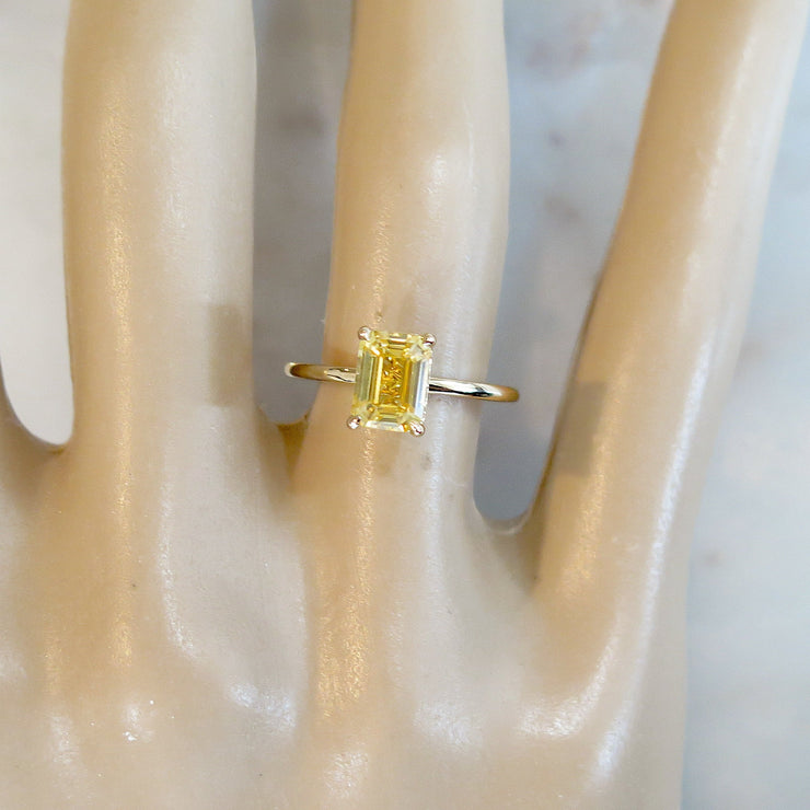 Yellow sapphire engagement ring in unique gold setting on hand in emerald cut