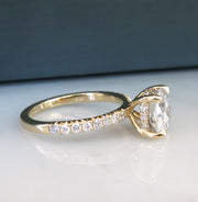 Diamond solitaire engagement ring in yellow gold with accent diamonds underneath stone and in band from side profile