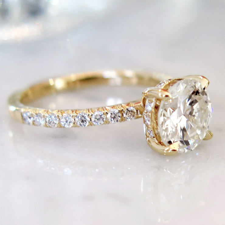 Delicate diamond solitaire in yellow gold with accent diamonds underneath center stone and micro-pave 