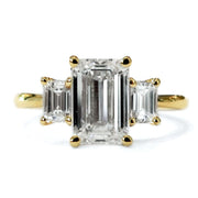 Classic 2 carat emerald cut three stone engagement ring in yellow gold with delicate band 