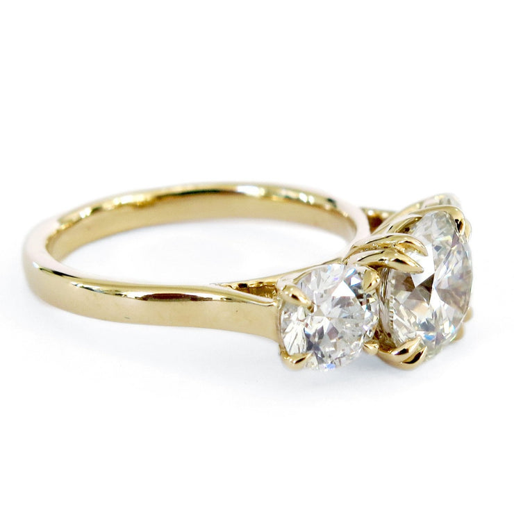 Side view of a three stone diamond ring with round brilliant cut diamonds set in yellow gold. Made in New York City.
