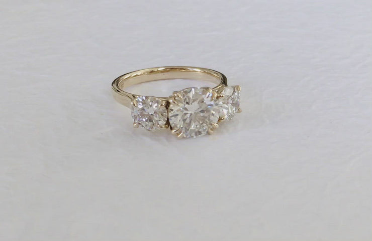 Video of the Dana Walden three-stone engagement ring named Victoria. Features a 2 carat round diamond flanked by two smaller diamonds. Made in New York City.