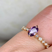 Purple sapphire engagement ring with delicate diamond band and NSEW prongs on hand by Dana Walden Bridal NYC