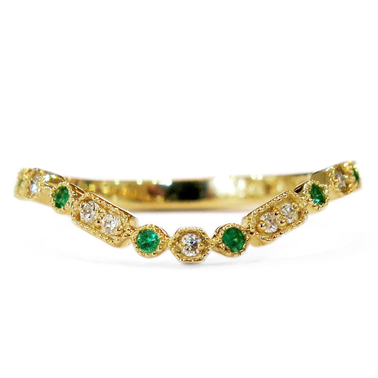 A gently curved emerald and gold wedding ring set in yellow gold. DANA WALDEN BRIDAL NYC.