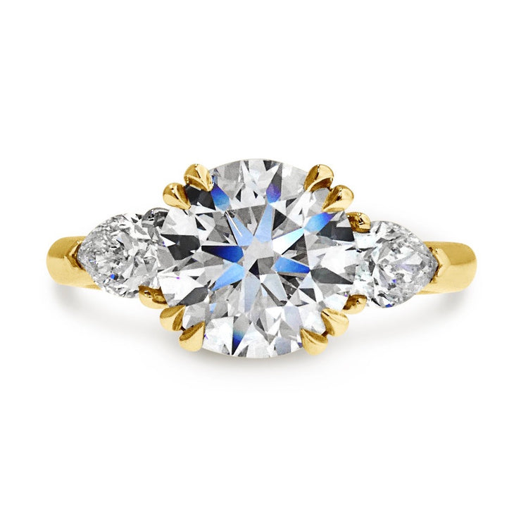 Three stone engagement ring with round diamond at center flanked by two pear shaped diamonds, set in yellow gold. Ethically handmade in New York City by Dana Walden Jewelry.