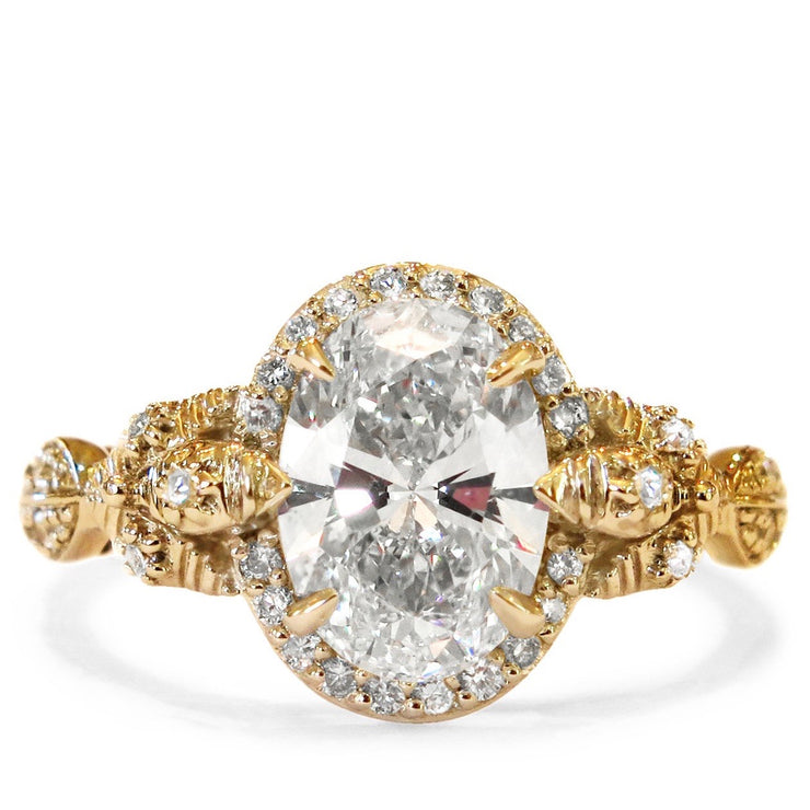 An oval diamond solitaire with leafy nature inspired details and conflict-free diamond accents. Yellow Gold engagement ring made in New York City by Dana Walden Bridal.