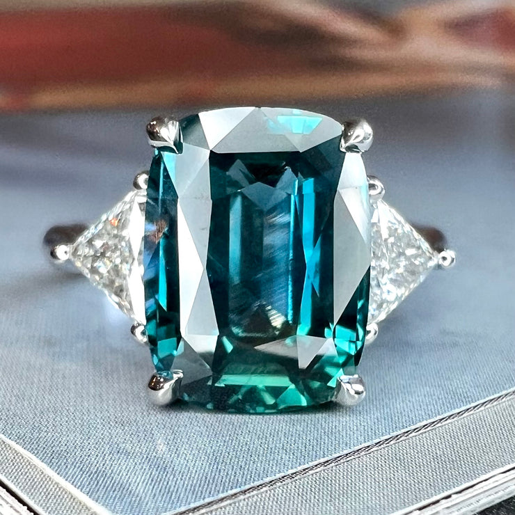 Cosette 5.11 carat natural teal sapphire and diamond engagement ring in three stone design with natural trilliant triangular side diamonds and cushion cut sapphire set in platinum