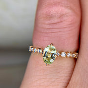 Light green sapphire engagement ring in yellow gold with diamond accents and NSEW compass prongs on hand by Dana Walden Bridal NYC