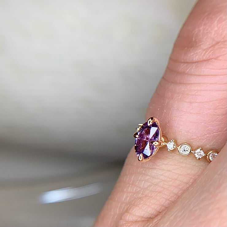Purple sapphire engagement ring with diamond accents on hand in yellow gold by Dana Walden Bridal NYC