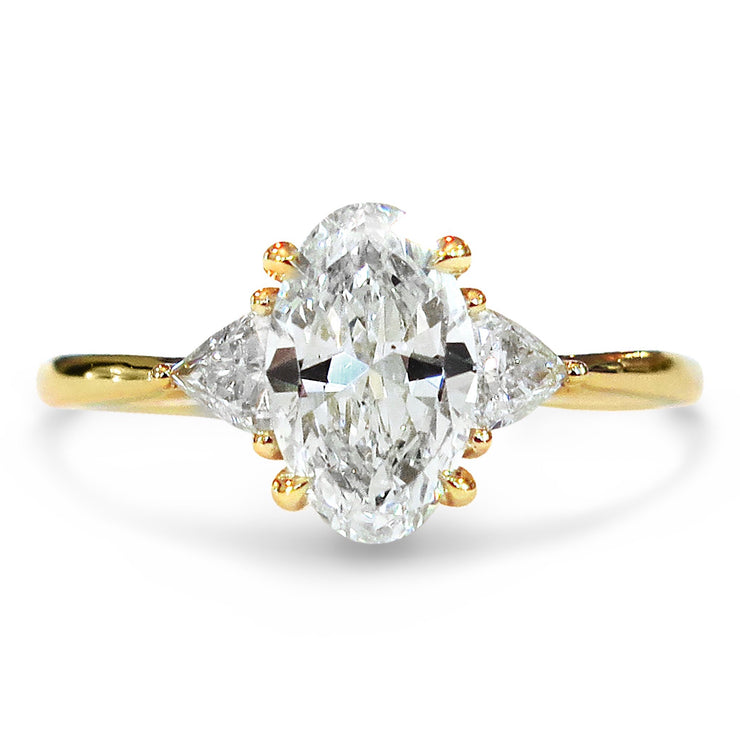 Lucine oval cut diamond 3 stone engagement ring in yellow gold with trillion side stones on hand