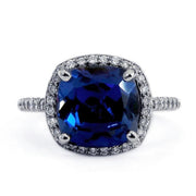 Cushion cut deep blue sapphire engagement ring with diamond halo. By Dana Walden Bridal NYC.